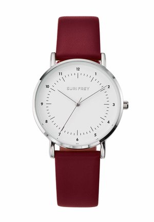 Round silver wristwatch with white dial, black hour markers, three thin hands, and a dark red leather strap. Brand name "SURI FREY" visible.