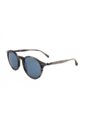 Occhiali da sole rotondi con lenti sfumate blu e montatura e astine in plastica grigia traslucida con motivo su sfondo bianco.