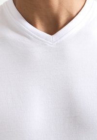 Witte katoenen V-hals t-shirt met een gladde textuur, een relaxte pasvorm en een eenvoudig ontwerp zonder patronen of versieringen.