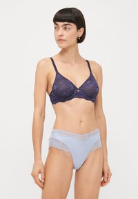 Marinblå spets-bralette med blommönster och underwire; matchas med ljusblå trosor med spetsdetaljer och utskärningar vid höfterna.