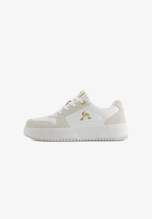 Sneaker bianco con dettagli in suede, punta tonda e suola testurizzata. Presenta un logo dorato, lacci bianchi e un colletto imbottito per il comfort.
