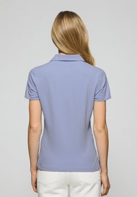 Ljuslila polo skjorta med krage och korta ärmar, med en figurnära design och slät textur, bärs med vita byxor.