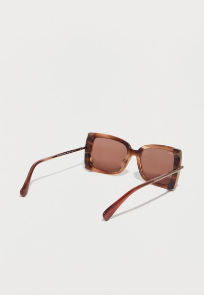 Γυαλιά ηλίου oversized σε σχήμα τετραγώνου με σχέδιο χελώνας και καφέ φακούς, τοποθετημένα πάνω σε λευκή επιφάνεια.