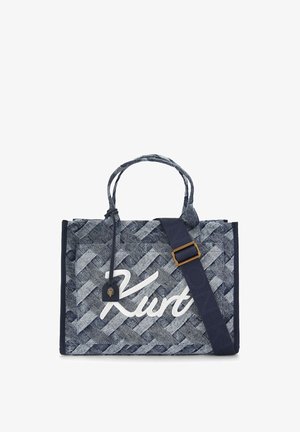 Sac cabas à motif tissé bleu avec le nom "Kurt" écrit en écriture blanche, deux poignées courtes et une bandoulière réglable bleu foncé avec une boucle dorée.