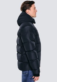 Jūras spēku pūkains mētelis ar kapuci, ar quilted sekcijām siltuma nodrošināšanai, elastīgām aprocēm un gludu, ūdensizturīgu ārpusi.