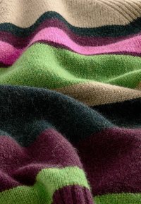 Tissu tricoté doux avec des rayures ondulées en beige, vert foncé, rose, vert et bordeaux.