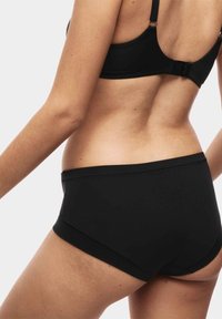 Set di reggiseno e slip neri senza cuciture, realizzato in tessuto morbido. Presenta spalline regolabili e un design a vita alta. Linee pulite, senza accessori visibili.
