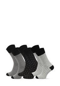 Zestaw czterech skarpetek: czarne w paski, jednolite czarne z białymi kropkami, szare z czarnymi wzorami oraz białe z czarnymi motywami. Wszystkie z czarnymi ściągaczami.
