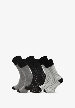 Zestaw czterech skarpetek: czarne w paski, jednolite czarne z białymi kropkami, szare z czarnymi wzorami oraz białe z czarnymi motywami. Wszystkie z czarnymi ściągaczami.