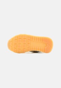 Semelle extérieure en caoutchouc avec une surface orange texturée, présentant un motif en grille et un bord renforcé pour une traction et une durabilité accrues.
