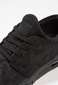 Baskets Nike noires avec tige texturée, dotées d'une languette rembourrée, de lacets et d'un logo emblématique. Semelle en mousse légère avec trous de ventilation.