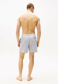 Gestreifte Badeshorts in Hellblau und Weiß, mit einem elastischen Bund und einer Gesäßtasche. Das Material scheint leicht und atmungsaktiv zu sein.