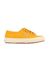 Sneakers in tela di un vivace giallo con suola in gomma bianca e suola esterna testurizzata marrone. Presenta cinque asole e un'etichetta con marchio sul lato.