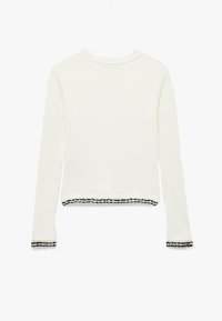 Weißes, geripptes Langarmoberteil mit cropped Länge, verziert mit schwarzen, gezackten Akzenten am Saum und an den Bündchen. Weicher Stoff, runder Ausschnitt.