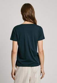 Mörkblå kortärmad t-shirt med rund halsringning, slät yta och avslappnad passform, parat med ljusrandiga byxor.