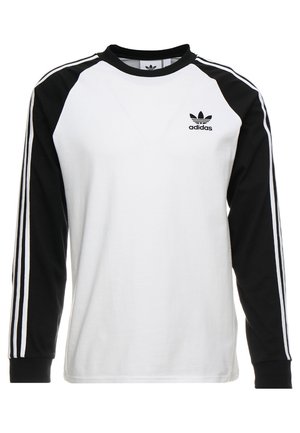 Długorękawowa koszulka Adidas z białym korpusem, czarnymi rękawami z trzema białymi paskami oraz logo Adidas na lewej piersi.