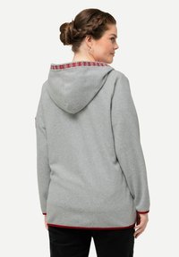 Grauer Kapuzenpullover mit roten Akzenten, der einen dekorativen gemusterten Rand um die Kapuze aufweist. Weicher Stoff und leicht verlängerte Rückseite.