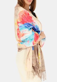 Kolorowa kwiecista chusta z miękkiej tkaniny; ozdobiona żywymi czerwonymi, niebieskimi i żółtymi wzorami oraz frędzlami na brzegach.