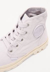 Light purple canvas ankle boot with metal eyelets, textured surface, and a cream rubber sole; features a circular logo on the side.