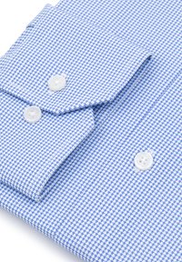 Złożona niebiesko-biała koszula w mały wzór houndstooth z białymi guzikami na mankietach i widocznym przodzie.