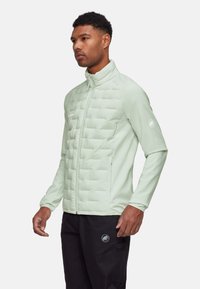 Miętowa kurtka puchowa z pikowanym przodem, gładkimi rękawami, wysokim kołnierzem i zamykanymi kieszeniami. Posiada subtelne logo na klatce piersiowej.