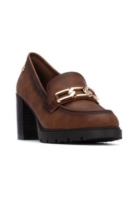 Mocasines de cuero marrón con detalle de cadena dorada, tacón negro grueso, punta redondeada y parte superior texturizada. Presenta un dibujo pronunciado en la suela.