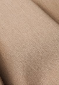 Beżowa tkanina o gładkiej fakturze, prezentująca subtelny diagonalny splot. Miękka i lekka, odpowiednia do różnych zastosowań.