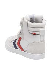 Wysokie trampki z białej skóry z miękkimi, szarymi zamszowymi akcentami. Posiadają czerwono-granatowy wzór w jodełkę, teksturowany kołnierz oraz gumową podeszwę.