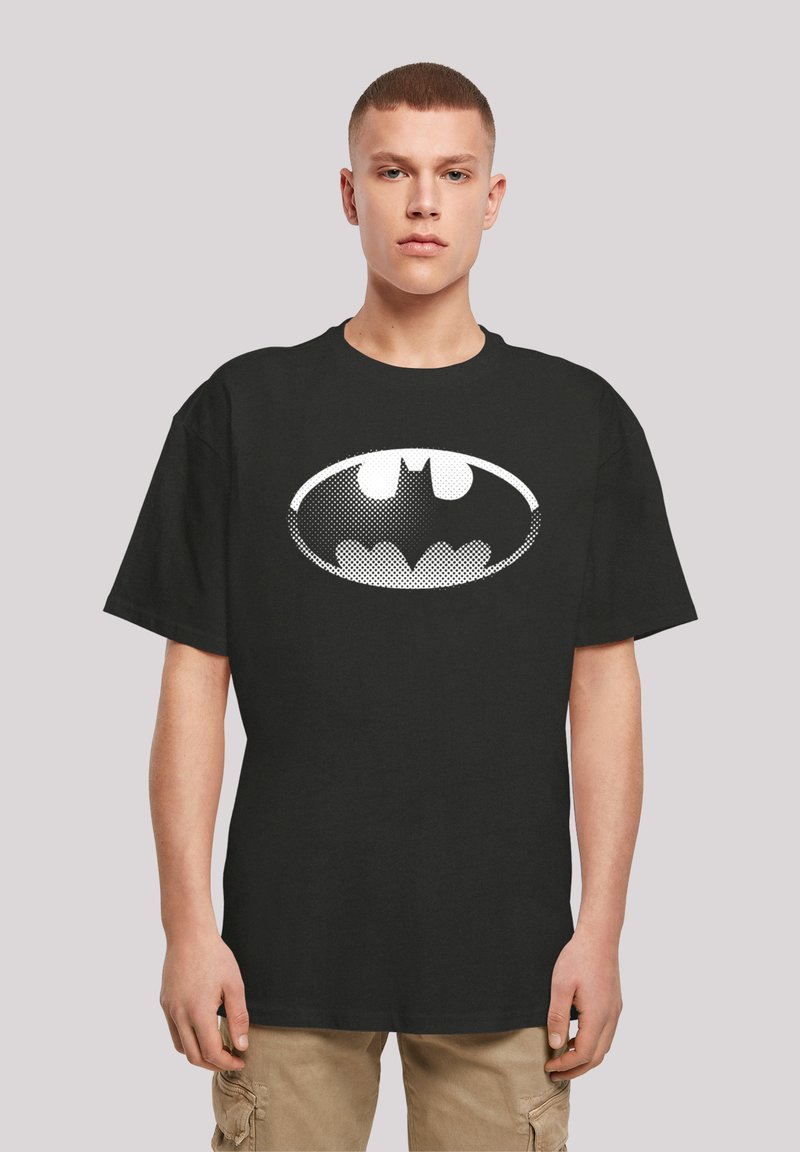 Svart t-skjorte i bomull med et stort hvitt Batman-logo i prikkete mønster, rund hals og korte ermer. Vanlig passform.