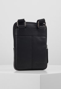 Borsa a tracolla nera in pelle con una texture liscia, chiusura con zip, due attacchi per la tracolla e logo in rilievo sulla parte anteriore.