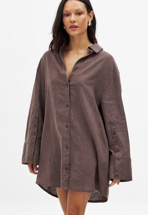 Abito camicia in lino marrone con vestibilità rilassata, maniche lunghe, chiusura frontale a bottoni e orlo arrotondato. Tessuto texturizzato.