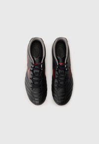 Black soccer shoes with textured leather upper, red accents, and grey lining. Features traditional lace closure and streamlined design.