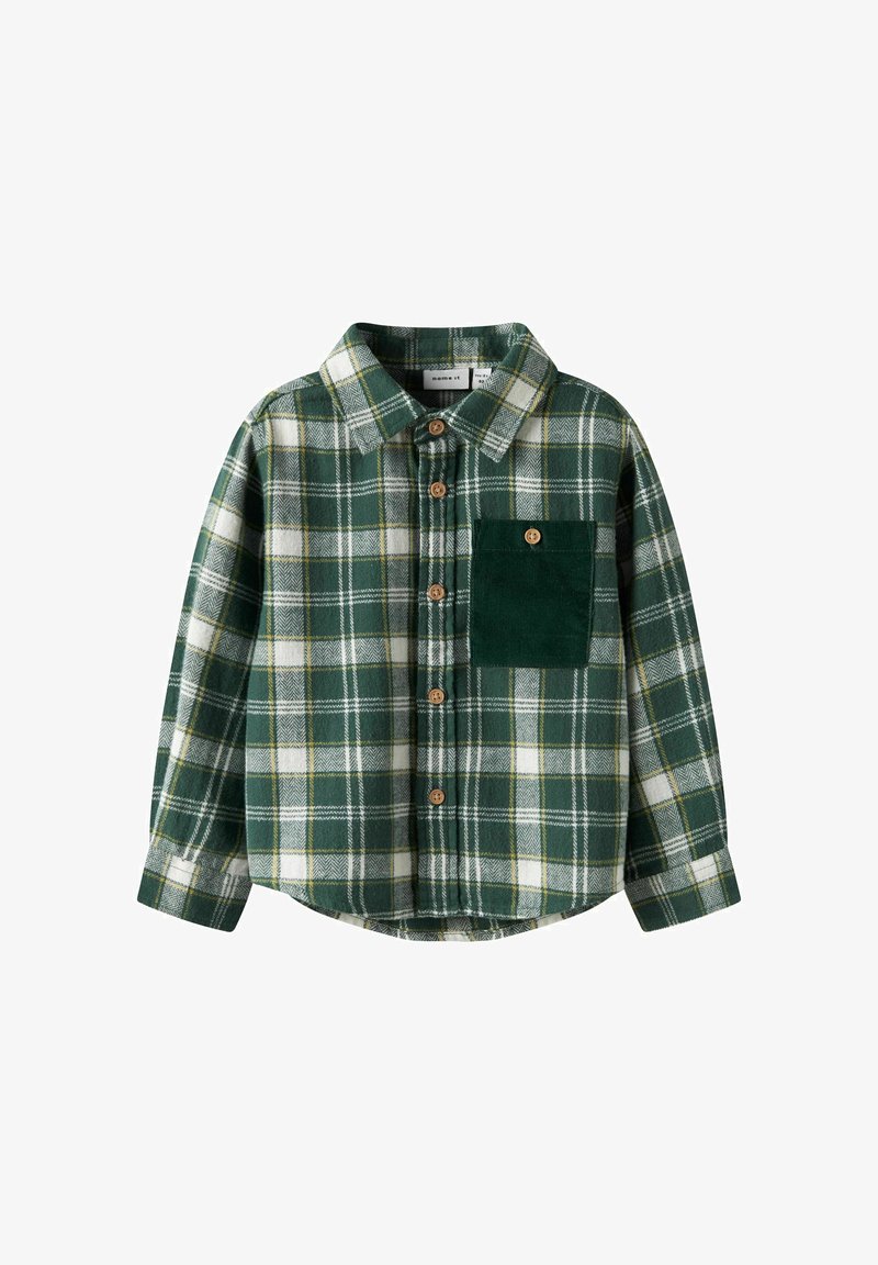 Camisa de franela de cuadros verdes con detalles en blanco y amarillo, cierre de botones al frente y un bolsillo de pana verde texturizado en el pecho izquierdo.