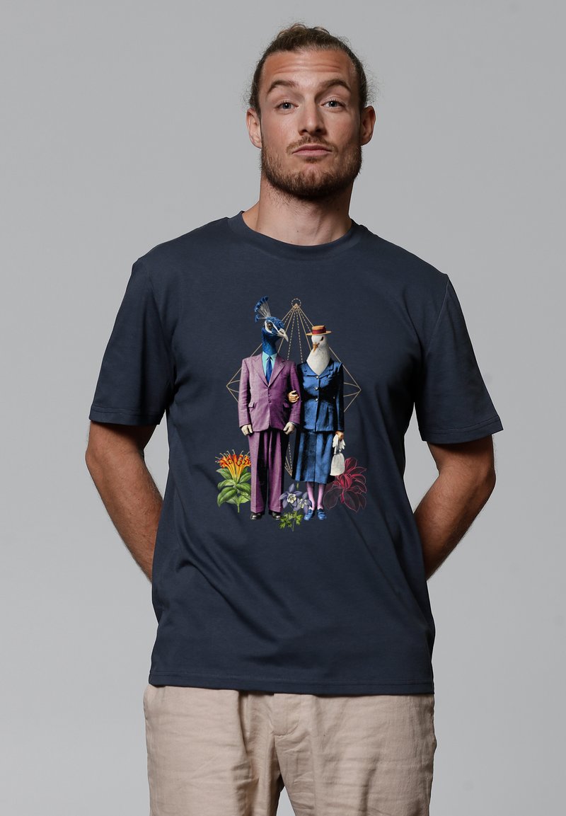 Marineblaues T-Shirt mit einem grafischen Motiv von zwei anthropomorphen Vögeln in formeller Kleidung, umgeben von bunten Blumen und geometrischen Formen.