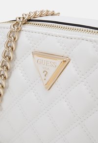 Borsa bianca trapuntata in pelle sintetica con tracolla a catena dorata. Presenta una targhetta triangolare in metallo dorato con logo sul davanti.