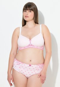Ljust rosa lingeriset med en mjuk bh som har en central rosett som accent, tillsammans med matchande trosor prydda med rosa rosett mönster och spetsdetaljer.