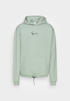 Lys grøn hoodie lavet af blødt stof, med en kængurulomme, snøre ved kanten og et sort logo på brystet.