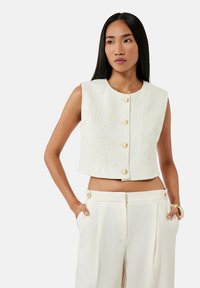Gilet bianco corto con tessuto testurizzato e design ricamato, caratterizzato da bottoni dorati rotondi e scollatura rotonda.