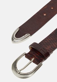 Cinturón de cuero marrón con un diseño texturizado, hebilla de metal en tono plateado y extremo puntiagudo. Costuras visibles y agujeros para un ajuste ajustable.