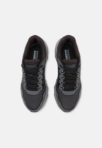 Czarne i szare sportowe buty z siateczkowymi panelami, zaokrąglonym noskiem, grubą podeszwą oraz wielokolorowymi sznurowadłami. Logo na języku i boku.