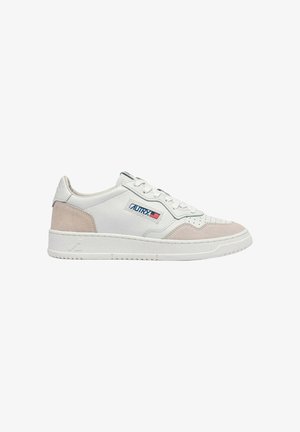 Zapatilla blanca de perfil bajo con acentos en ante beige, cierre con cordones y un parche con el logo de la bandera estadounidense en el lateral.