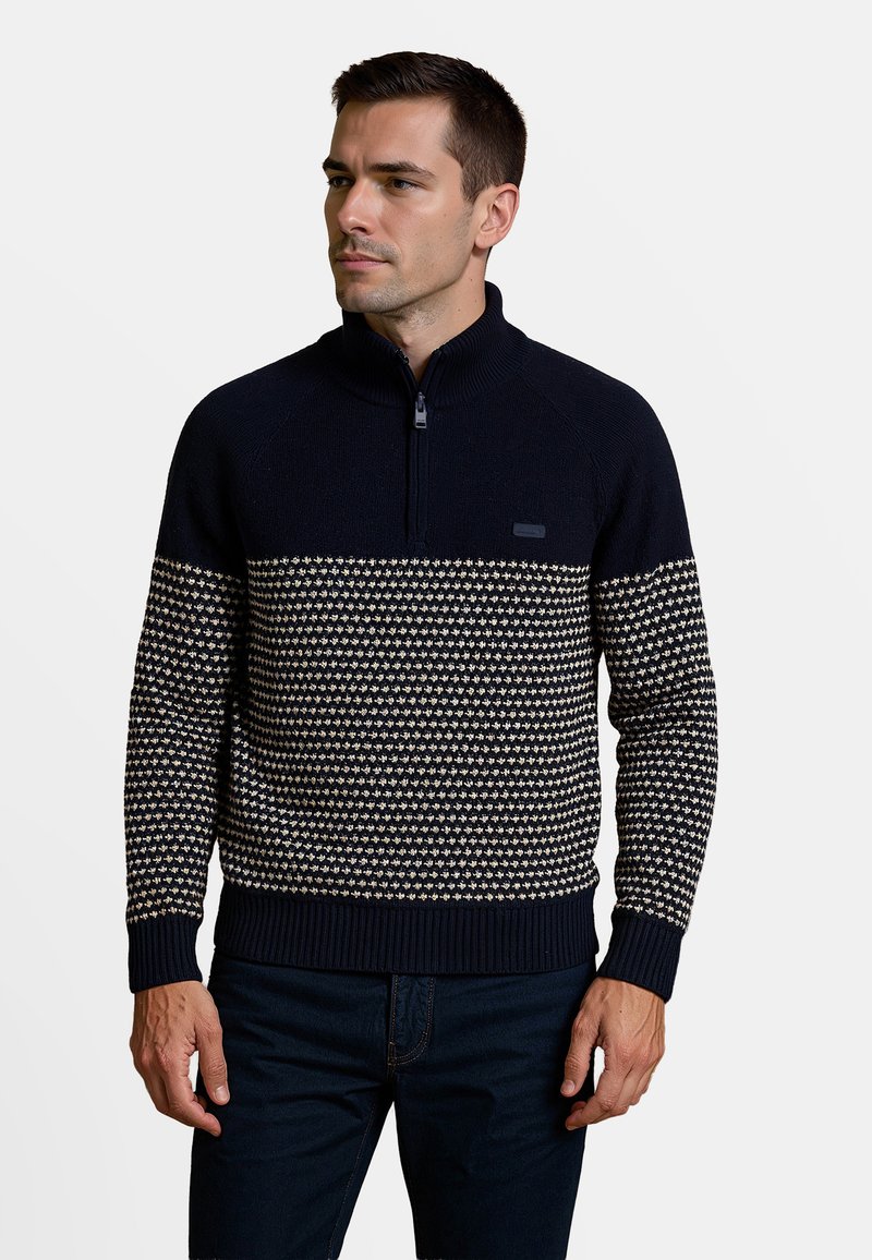 Marineblauwe pullover trui met half-rits kraag, voorzien van een crèmekleurig geometrisch patroon over de borst, geribbelde manchetten en zoom.