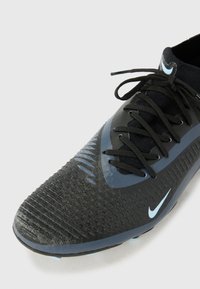 Melna un zila Nike futbola kurpe ar teksturētu sintētisku virsu, auklu aizdari un gumijas zoli. Raksturīga gluda, izsmalcināta dizaina forma.