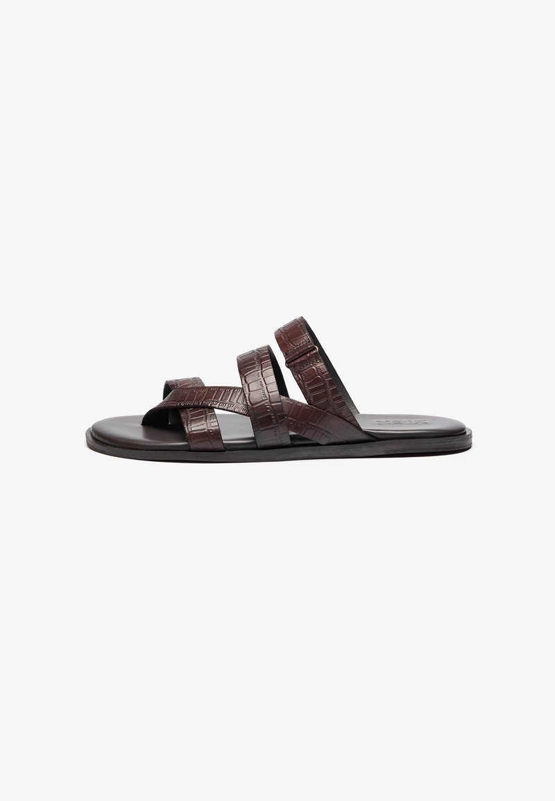 Brown leather sandals featuring three wide, textured straps with a cross design, flat sole, and subtle crocodile pattern detail.