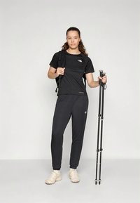 Sort atletisk t-skjorte og bukser, begge med North Face-logo. Buksene har en slank passform. Inkluderer en ryggsekk og fjellstaver.