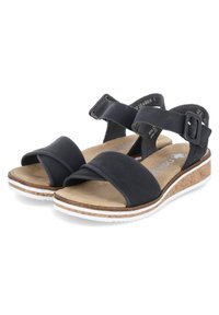 Black sandals with rubber straps, crisscross design at the front, cork midsole, white sole detailing, and adjustable buckles for fit.