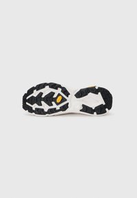 Semelle de chaussure de sport avec un motif de bande de roulement en caoutchouc noir, présentant un intercalaire blanc et un détail de logo jaune près du talon, texturée pour une meilleure adhérence.
