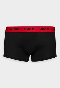 Schwarze Boxer-Badeshorts mit einem roten elastischen Bund, auf dem "HUGO" in Schwarz gedruckt ist. Hergestellt aus glattem Baumwollstoff mit einer figurbetonten Passform.