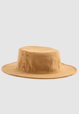 Sombrero de cubo de algodón marrón con corona plana, ala ancha, superficie texturizada y una pequeña etiqueta de logotipo roja. Presenta un patrón de cuadrícula.