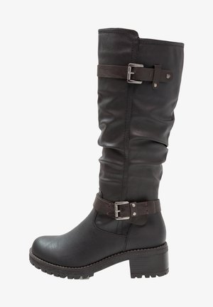 Černá kožená kozačka ke kolenu s volným střihem, plochým podpatkem a nastavitelným páskem se stříbrnou přezkou.